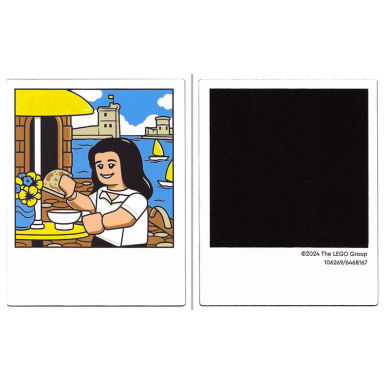 white plastic polaroid photo with minifigure with white shirt and black hair outdoor cafe water and castle and black square on back pattern