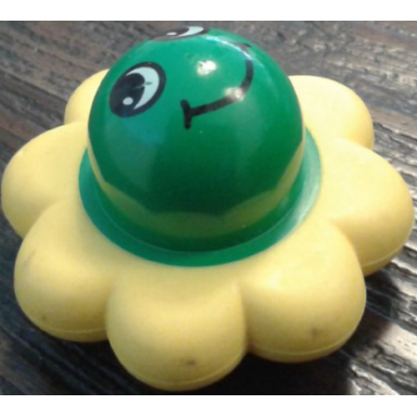 green primo rattle flower with 8 yellow petals and smiley face pattern